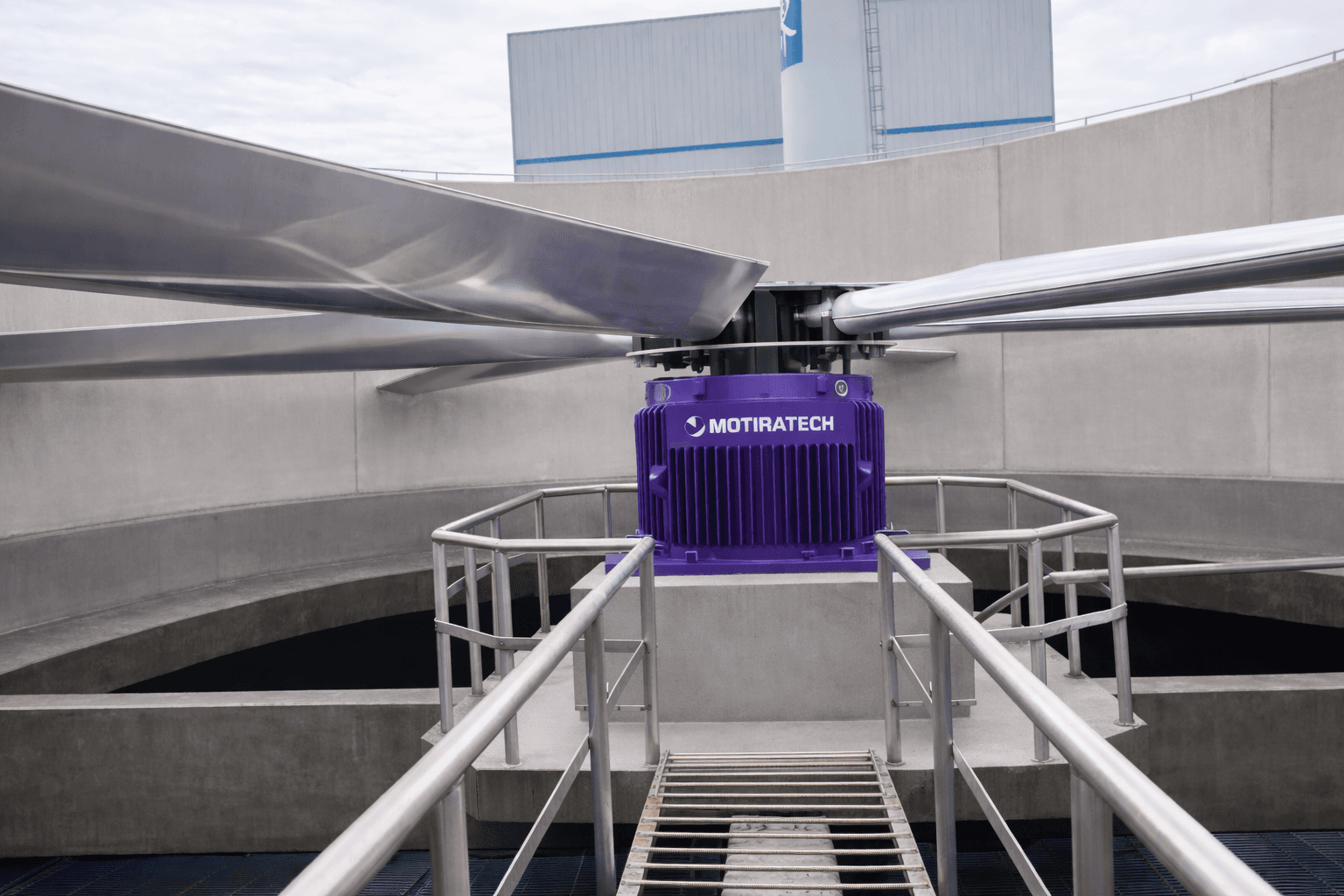 Large silver fan blades on a purple Motiratech motor inside a concrete cooling tower.