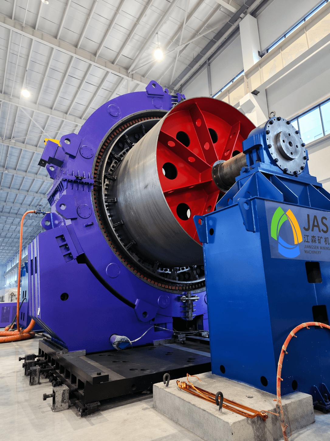 Large purple and blue Jiangsen mining machinery with a red spoked wheel in a factory.